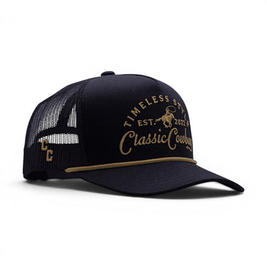 Classic Cowboy The Outpost all-black mesh back trucker hat with tonal gold embroidery and rope detail.