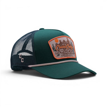 Classic Cowboy The Trailhead deep green mesh back trucker hat with western landscape patch and white rope detail.