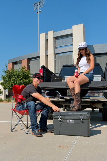 Couple at a stadium tailgate wearing Classic Cowboy Texas Tech snapbacks, including The Llano.