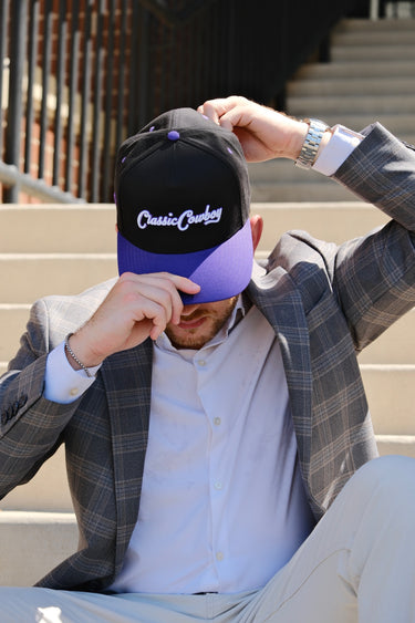 Man in a sport coat wearing the Classic Cowboy Panther black and purple snapback.