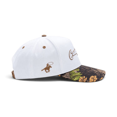 Classic Cowboy The Waylon white snapback with camo brim, side view of the bronc rider logo.